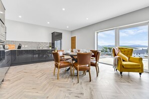 Una cocina moderna con zona de comedor, ventanas grandes y un sillón amarillo.