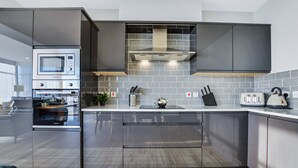 Et moderne køkken med indbyggede apparater, en stor ø og en backsplash af grå fliser.