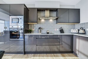 A modern kitchen with built-in appliances, a large island, and a backsplash of gray tiles.