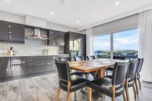Una cocina moderna con armarios oscuros, una campana extractora de acero inoxidable y un amplio ventanal con vistas a la ciudad.