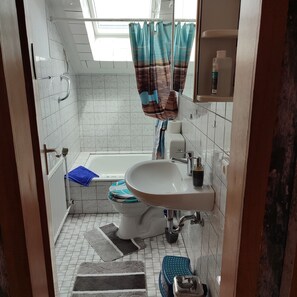 Une salle de bain avec un lavabo blanc, des toilettes, une baignoire et un espace douche.
