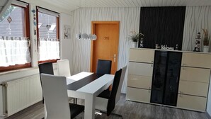 A compact room with a dining table, chairs, a cabinet, and a door. - Quietly located vacation apartment near the dike (Wurster Nordseeküste)