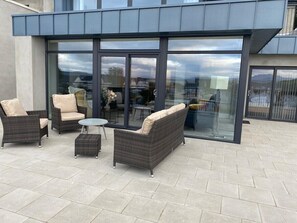 Un patio al aire libre con mobiliario de mimbre y un ventanal de vidrio que da a un edificio.