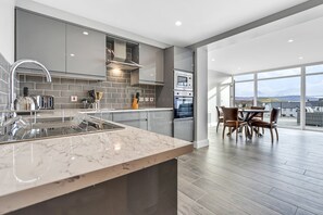 Una cocina moderna con gabinetes grises, encimera de mármol y comedor con vistas.