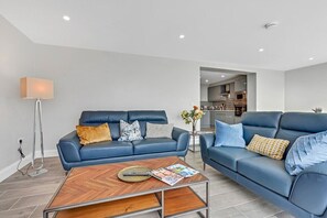 Una sala moderna con dos sofás de cuero azul, una mesa de centro de madera y una lámpara de pie.