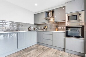 Una cocina moderna con armarios grises, un microondas de acero inoxidable y un horno.