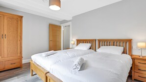 A bedroom with a large bed, wooden wardrobe, and bedside lamps. - Bayview Downings - Luxury 2 Bedroom Apartment (Downings)
