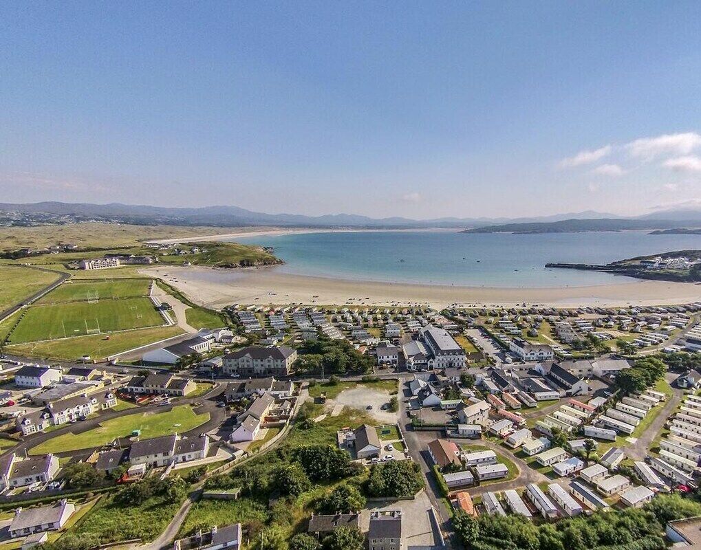 Eine Wohngegend an der Küste mit Häusern, einem Strand und blauem Himmel.