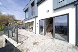 A modern building with large glass doors, a staircase, and a paved patio area.