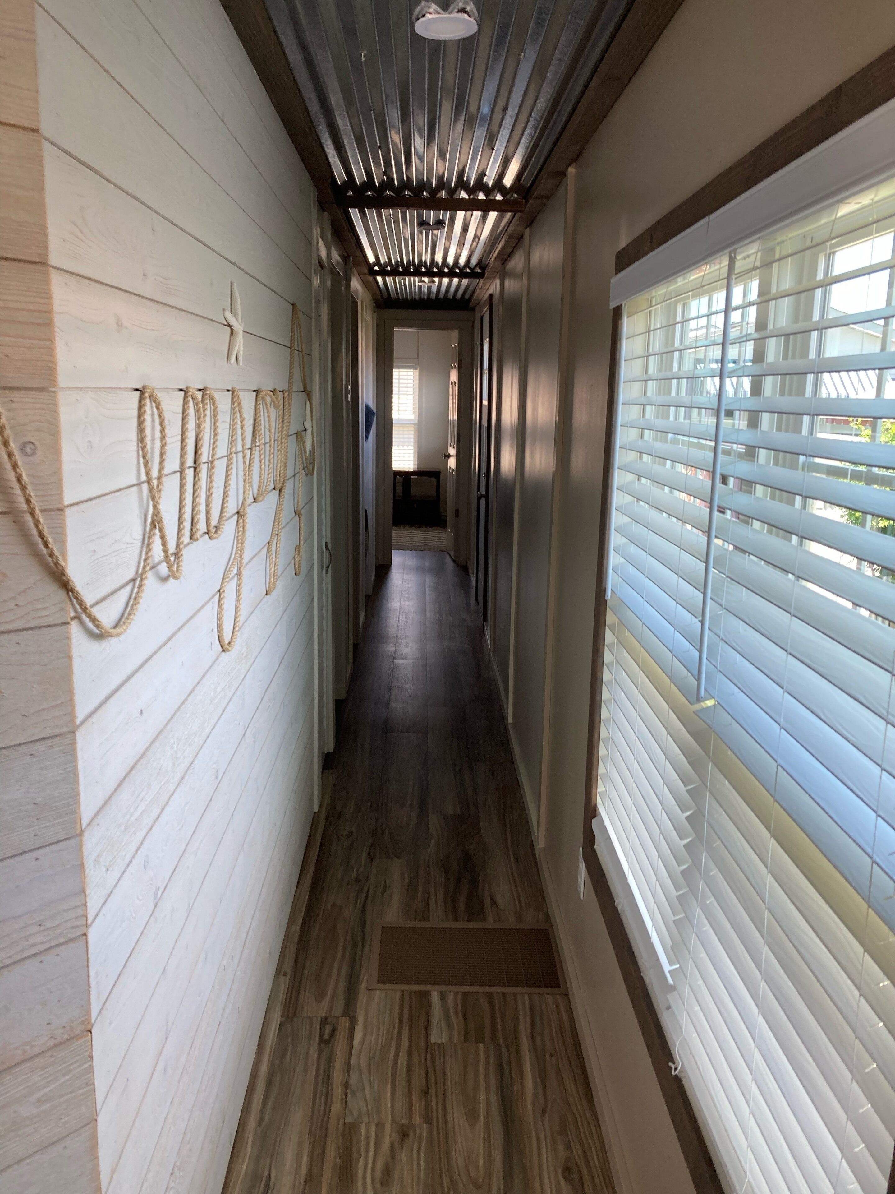 A hallway with wooden walls, a dark wooden floor, and a ceiling with exposed ductwork.
