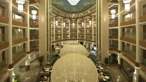 Un atrium d’hôtel à plusieurs niveaux, doté d’un espace central ouvert, de rampes en verre et d’un éclairage moderne.