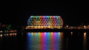 Un bâtiment doté d’une structure en forme de dôme, illuminé par des jeux de lumière colorés.