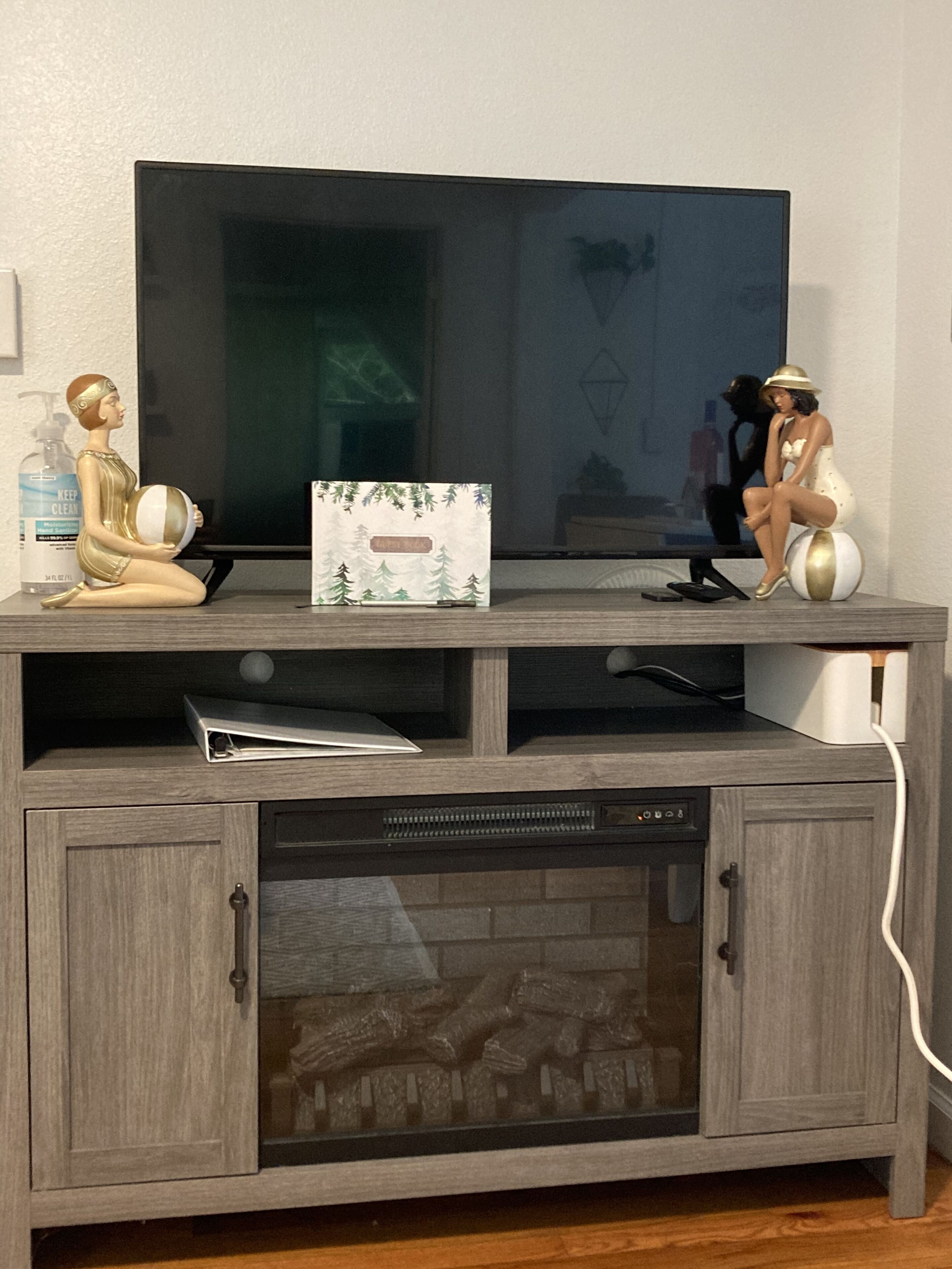 Un meuble de rangement en bois pour appareils multimédias, avec un téléviseur à écran plat, une figurine décorative et une petite boîte.