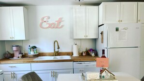 Eine moderne Küche mit weißen Schränken, einer Spüle, einer Kaffeemaschine und einem Kühlschrank.
