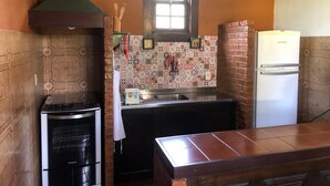 Cocina compacta con estufa a gas, refrigerador y ventana sobre el lavamanos.