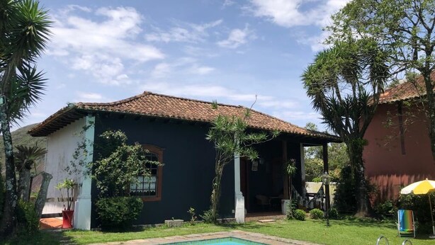 Una piscina con borde de baldosas, rodeada de un césped cuidado y una casa con tejado de cerámica.