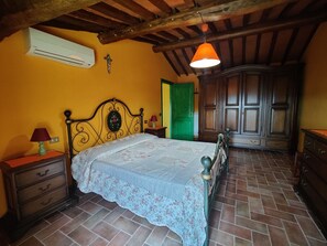 A bedroom with a bed, a nightstand, a dresser, a green door, and a wooden wardrobe.