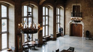 A spacious hall with arched windows, chandeliers, and wooden furniture. - Fairmont Banff Springs Gold Experience (Banff)
