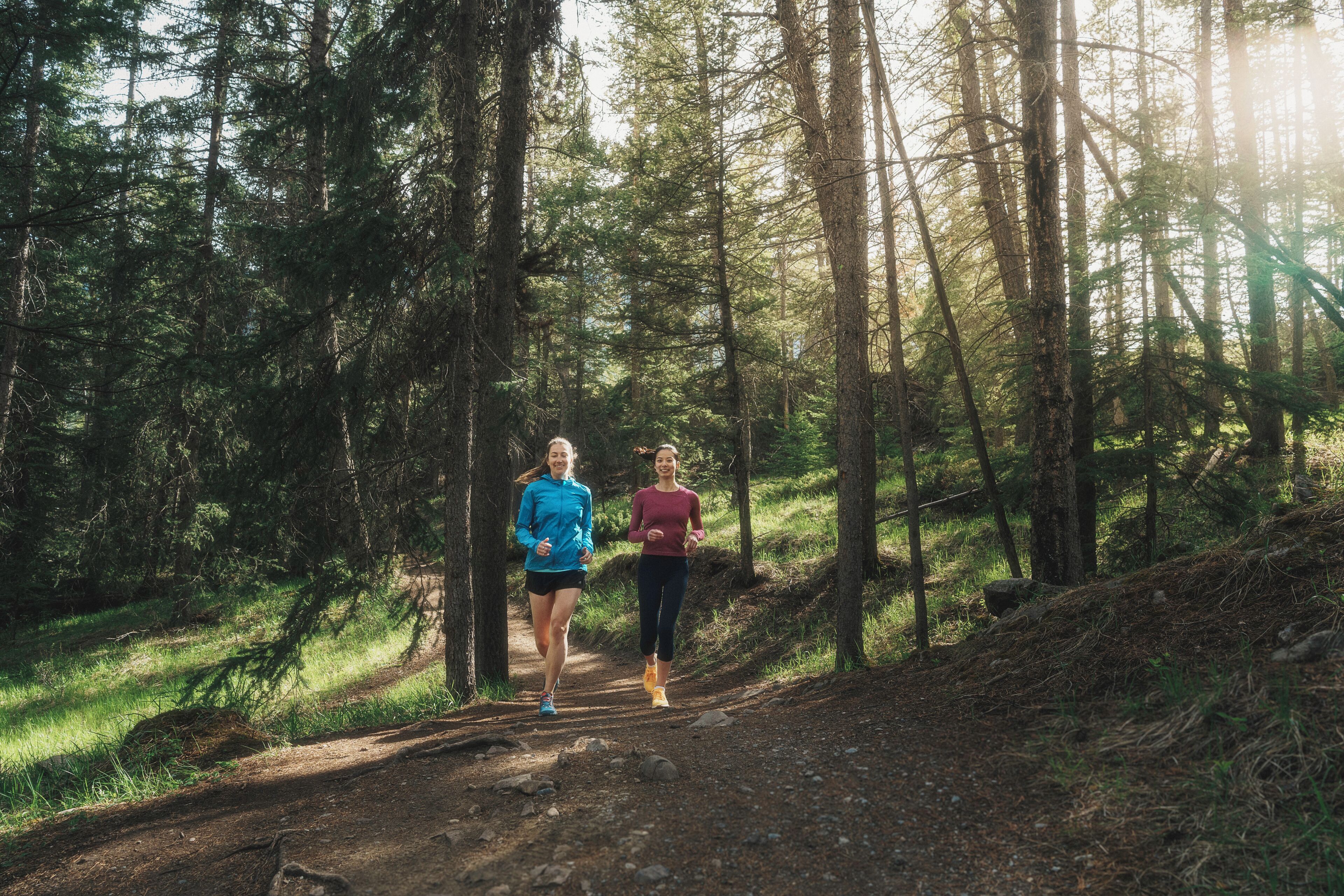 Two people jogging on a forest trail.