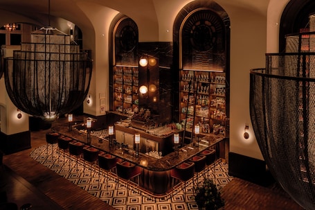 A bar area with a curved counter, bar stools, and shelves stocked with bottles.