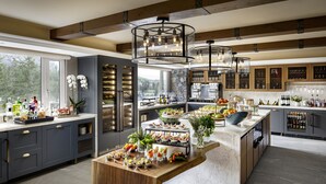 A modern kitchen with a central island, built-in wine racks, and large windows. - Fairmont Chateau Whistler Gold Experience (Whistler)
