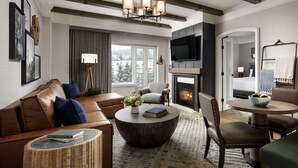 A modern living room with a fireplace, a sofa, a coffee table, and a TV mounted on the wall. - Fairmont Chateau Whistler Gold Experience (Whistler)