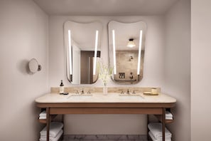 A bathroom with a double sink, two mirrors, a vase with flowers, and towels. - Fairmont Chicago at Millennium Park Gold Experience (Chicago)