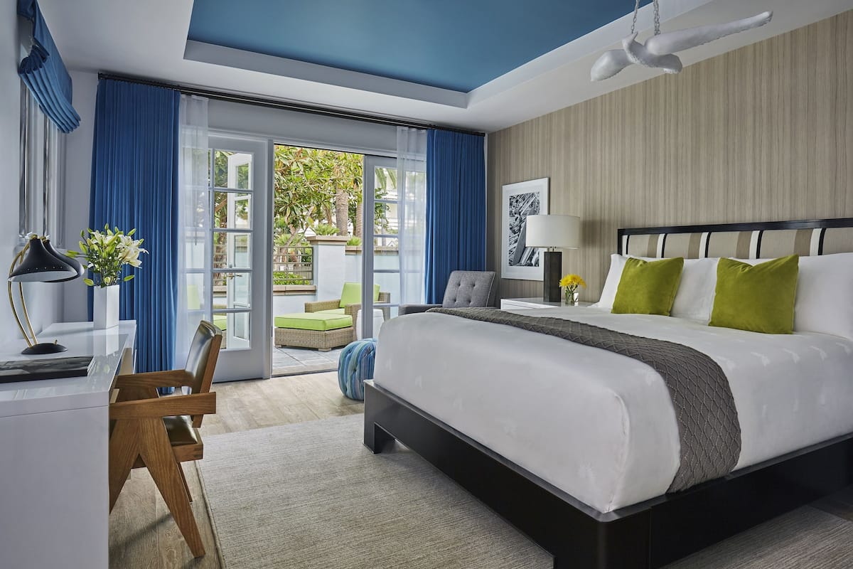 A modern hotel room with a large bed, a desk, and a view of the outdoors.