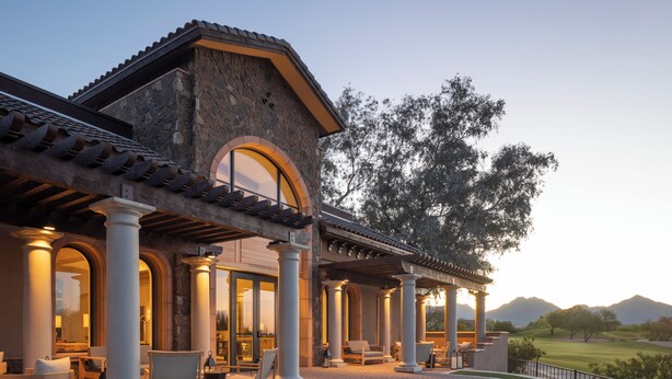 A building with a stone facade, large columns, and a covered patio area with outdoor seating. - Privado Villas at the Fairmont Scottsdale Princess (Scottsdale)