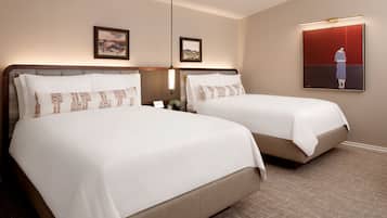 A hotel room with two beds, a large painting on the wall, and a clock on the nightstand.