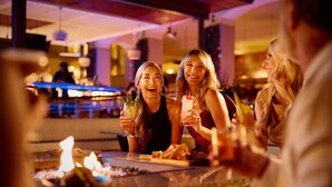 A bar area with a long counter, a fire feature, and a bartender in the background. - Privado Villas at the Fairmont Scottsdale Princess (Scottsdale)