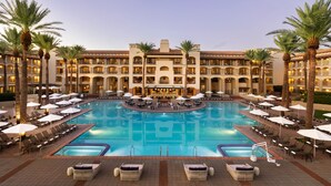 A hotel with a large central pool, multiple balconies, and palm trees. - Privado Villas at the Fairmont Scottsdale Princess (Scottsdale)