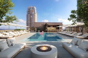A rooftop pool area with lounge chairs, a fire pit, and a view of a tall building. - Fairmont Century Plaza Gold Experience (Los Angeles)
