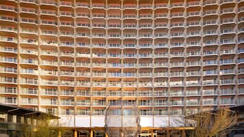 Un hôtel de grande hauteur à la façade uniforme, doté de nombreux balcons et d’une cour intérieure où se trouve une sculpture sphérique.