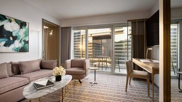 Une chambre d’hôtel moderne équipée d’un canapé, d’un fauteuil, d’une table basse et d’un bureau.