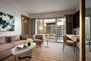 Een moderne hotelkamer met een bank, fauteuil, bijzettafeltje en bureau.