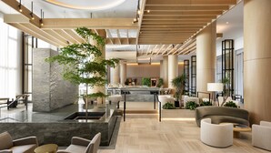 Un vestíbulo amplio con una recepción central, zonas de estar y una gran planta de interior.
