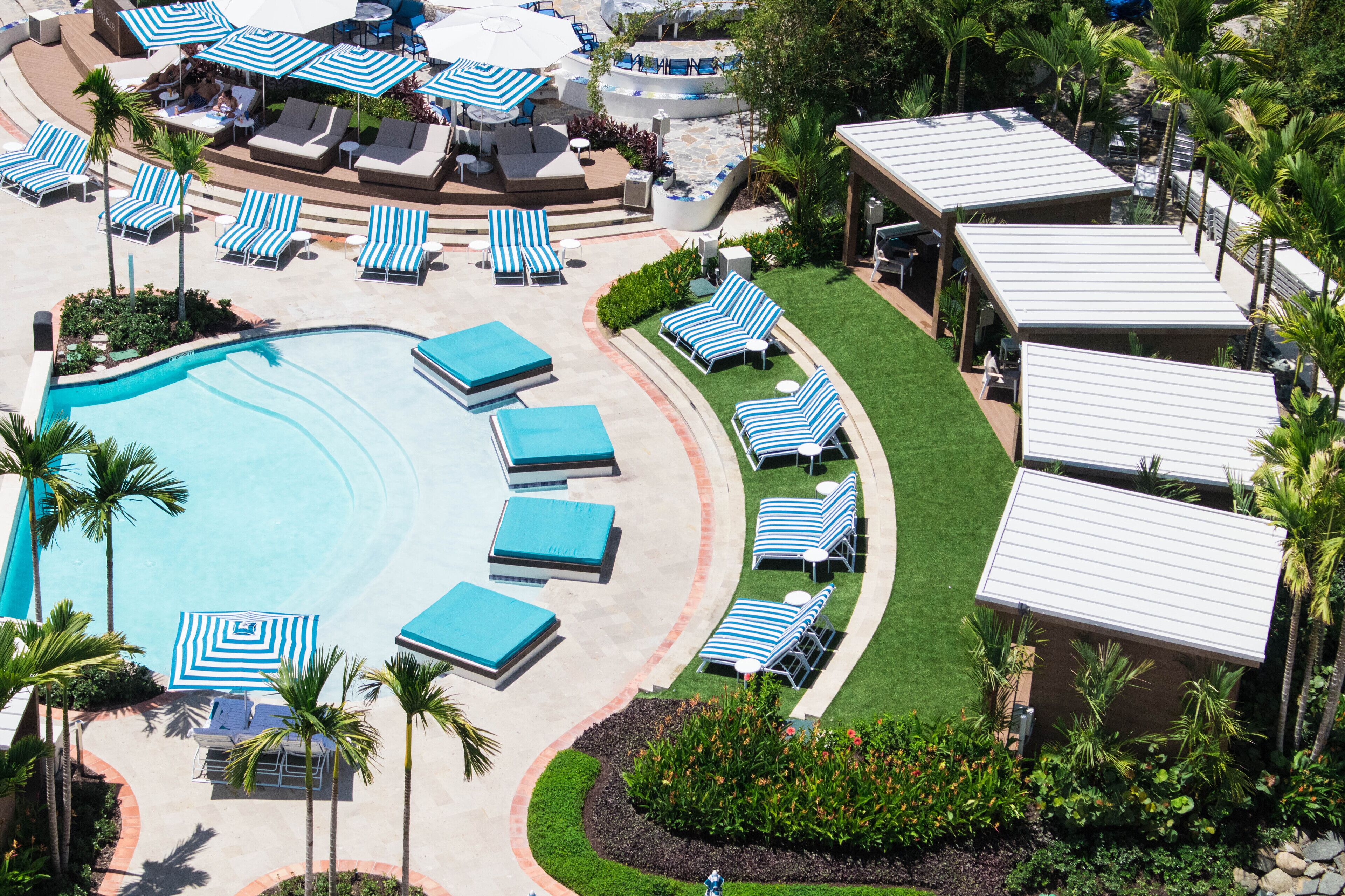 Un resort con piscina, sillones de descanso y sombrillas.