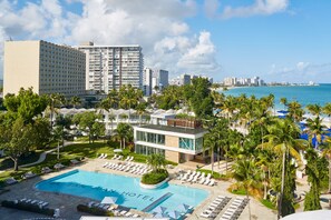 Un hotel con piscina, palmeras y vista al océano.