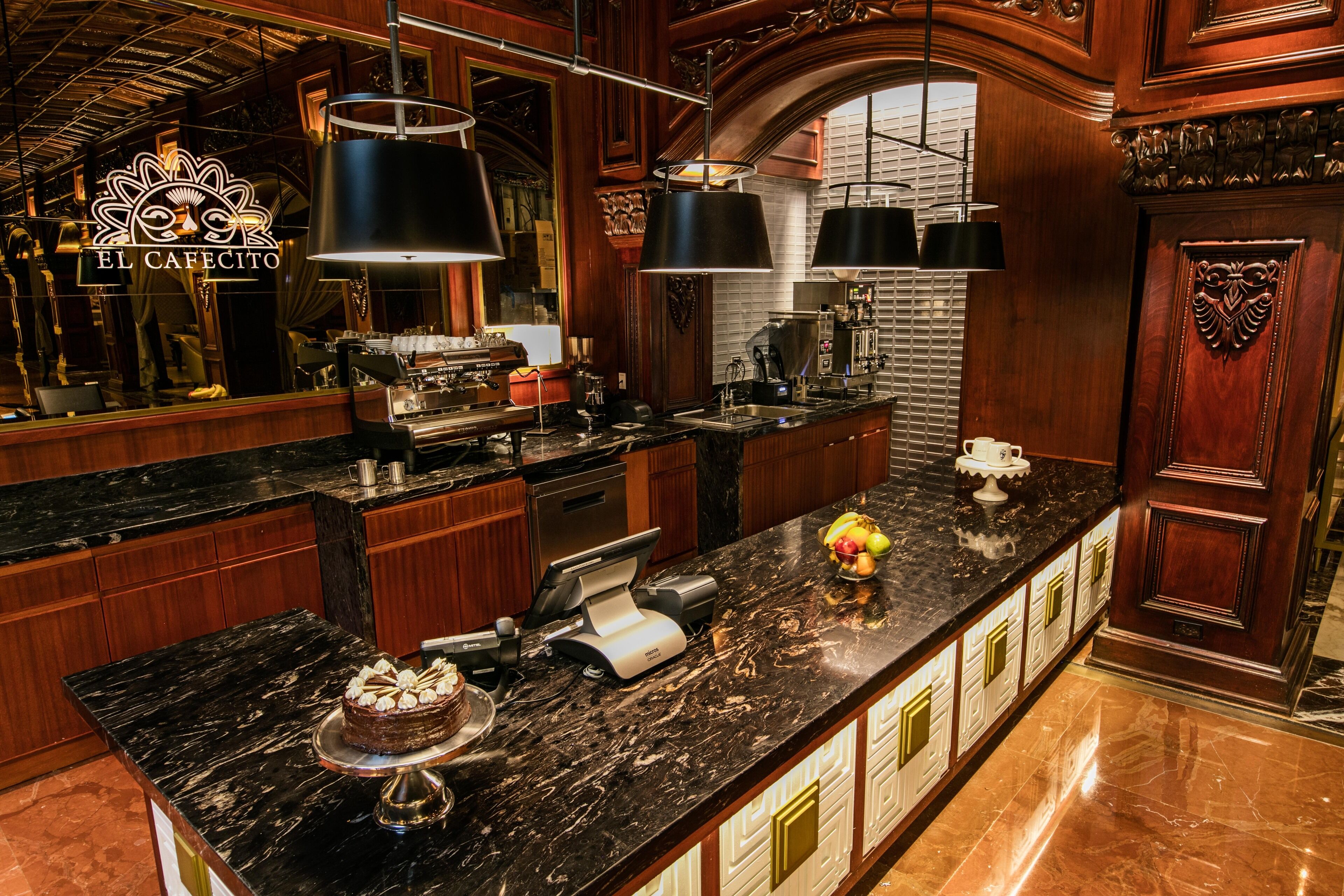 A luxurious kitchen with marble countertops, a coffee machine, and a fruit bowl.