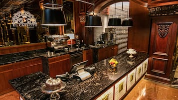 A luxurious kitchen with marble countertops, a coffee machine, and a fruit bowl.