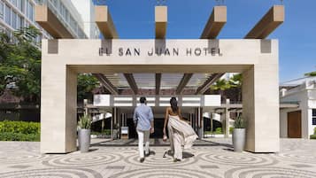 The entrance to El San Juan Hotel with a modern design, featuring a clear sign and a patterned floor.