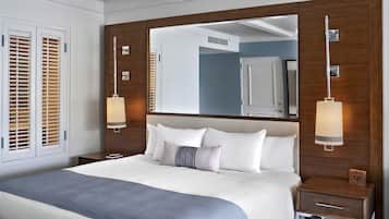 Ein modernes Hotelzimmer mit einem großen Bett, Holzpaneelen, einem großen Spiegel und zwei Nachttischlampen.