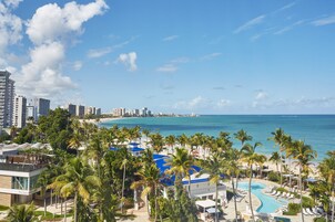 Un resort con piscina, palmeras y vista al mar.