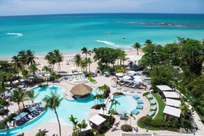 A resort with a large swimming pool, beach, and palm trees. - Fairmont El San Juan Villa Experience (Carolina)