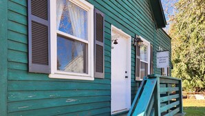 Une maison en bois peinte en vert, avec une porte blanche, un petit porche et une enseigne indiquant « ROBINSON RIVER ROOST ».