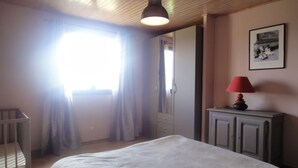 A bedroom with a bed, a bedside table with a lamp, a wardrobe, and a window with curtains. - Gite 6 people in a stone farmhouse, swimming pool, property 10Ha, panoramic view (Rocles)