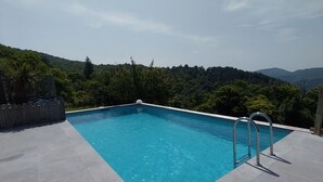 A rectangular swimming pool with clear blue water, surrounded by a tiled deck. - Gite 6 people in a stone farmhouse, swimming pool, property 10Ha, panoramic view (Rocles)