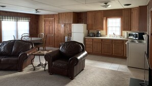 Un salón espacioso con chimenea, comedor con mesa y sillas, y cocina con armarios de madera y electrodomésticos.