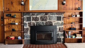 Una sala de estar acogedora con chimenea de piedra, estanterías de madera y un gran mapa en la pared.